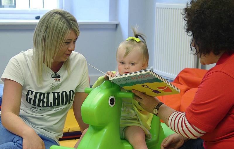 Mum and support worker read to a little girl